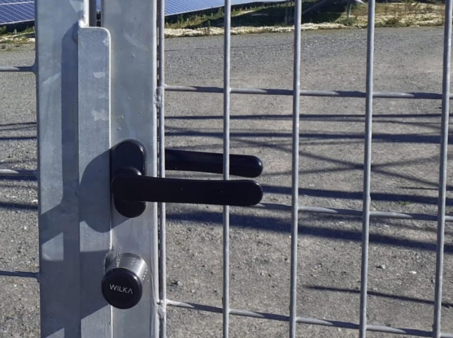 Detailed view of the WILKA easy electronic locking cylinder on a metal mesh gate