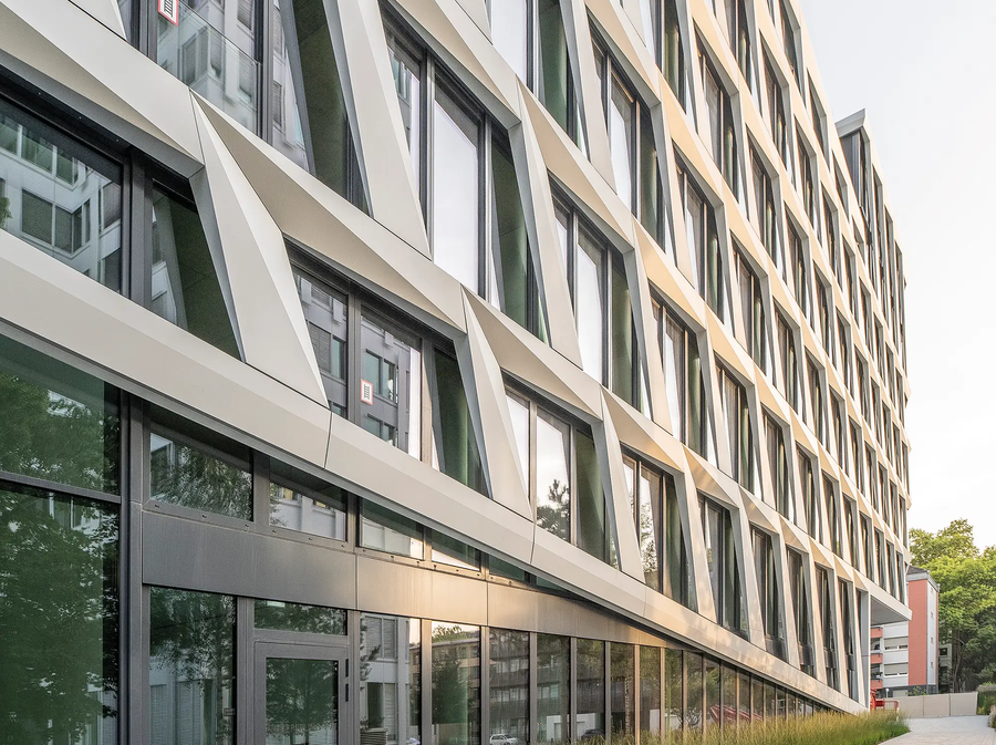 Side view of the ONE PLAZA building with a structured façade, large windows, and a landscaped front area.